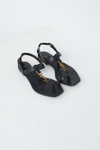 Saint Laurent Black Leather 
Gold Cassandra Flat Sandal